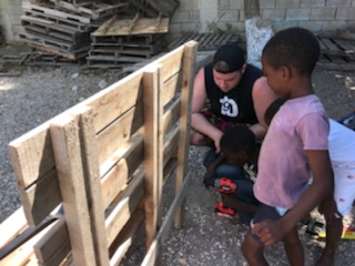 Student Service in Jamaica - A Student helps inspect a pallet used for building furniture